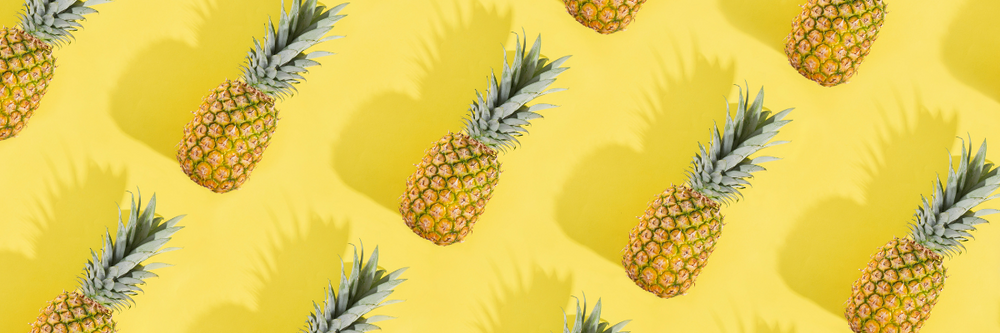 A header image featuring a bright yellow background and a repeating pattern of whole pineapples with a slight drop shadow. 